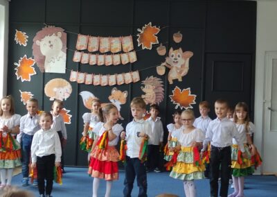 Dzieci występują na scenie z pomponami, świętując Dzień Edukacji Narodowej z motywami jeży.